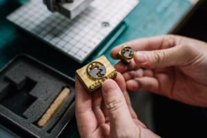 Close-up view of hands holding handcrafted brass stamps on a workbench.
